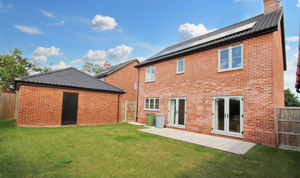 Residential Page - Marketing, image of the back of a modern brick property in norfolk, with a green lawn and enterance to a garage