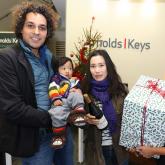 Chris and Yuki Russell with baby Toki receive their case of wine from Elisha Mace of Arnolds K eys